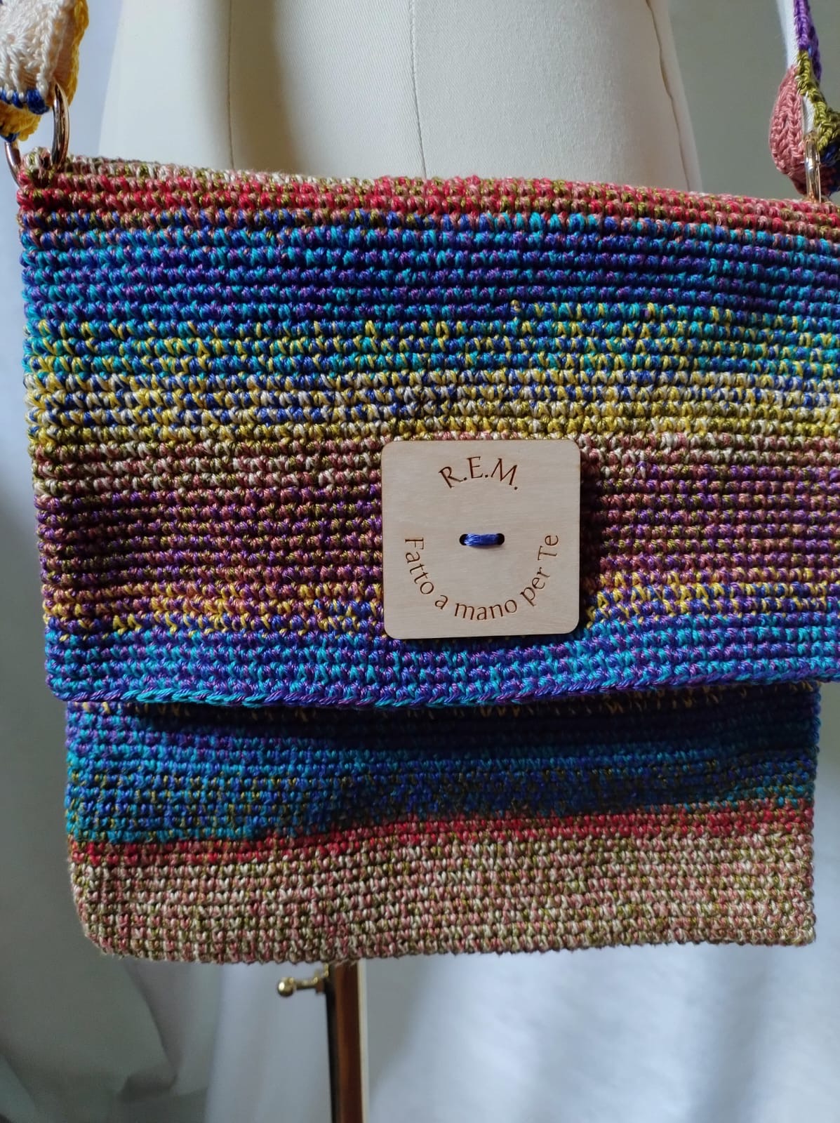 Antonia borsa. Realizzata in cotone. Tecnica uncinetto. Multicolore. Taschino interno ed esterno. Tracolla minipiastrelline. Moschettoni e bottone gigante.