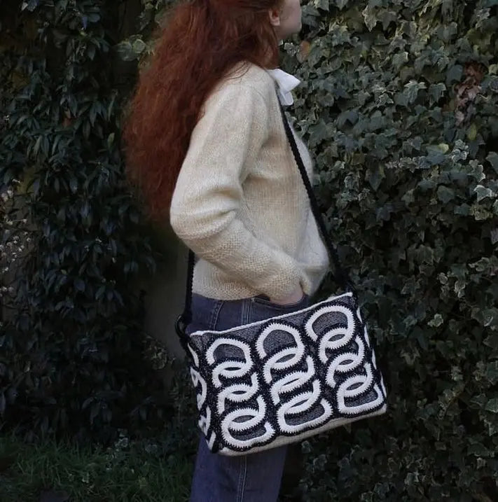 Esplora l'arte del portare con 'Luisa', la nostra borsa all'uncinetto in lana. Con un elegante motivo a cerchi Black and White, unisce spazio e stile per il tuo quotidiano.